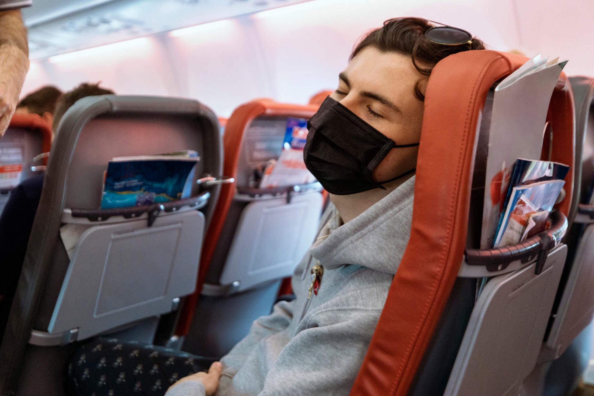 a man wearing a face mask while sitting on an airplane.