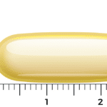 A Vitakruid – Fish Oil 1400 TG® with D3 softgel capsule, yellow and translucent, is shown next to a ruler, measuring about 2.3 cm in length.